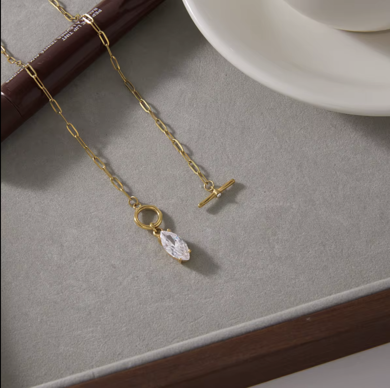 gold necklace with marquise gemstone pendant pictured on a grey background