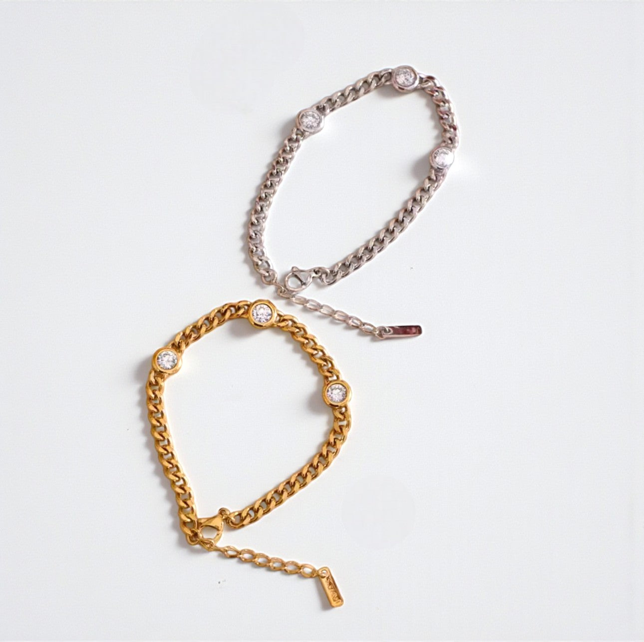 Gold and silver chain bracelets on a light grey background