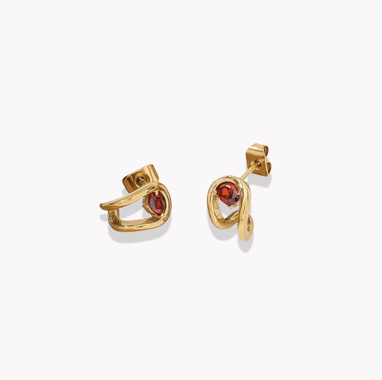 Gold earrings with red gemstones on a white background