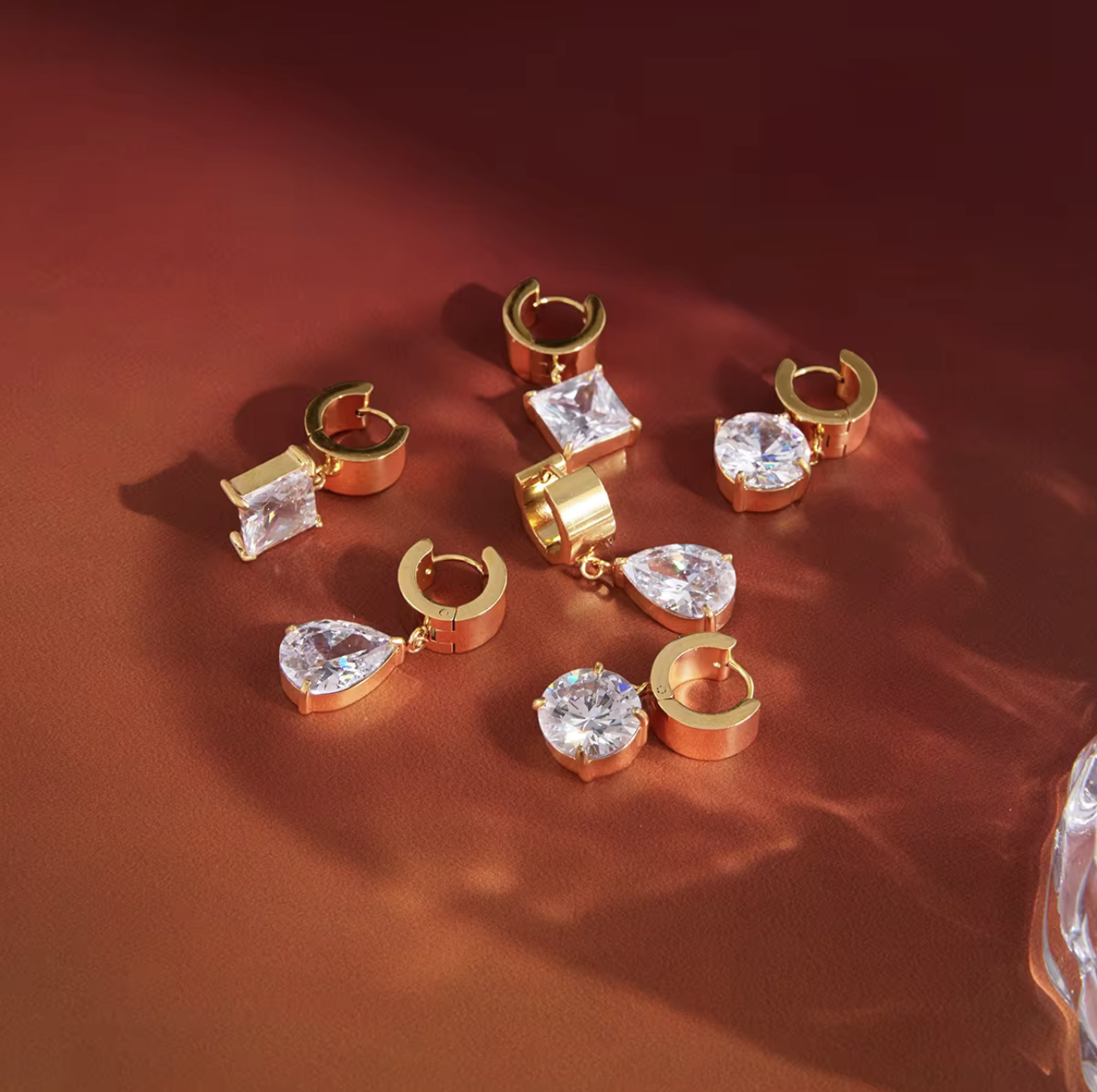 numerous gold earrings with gemstones on a red background