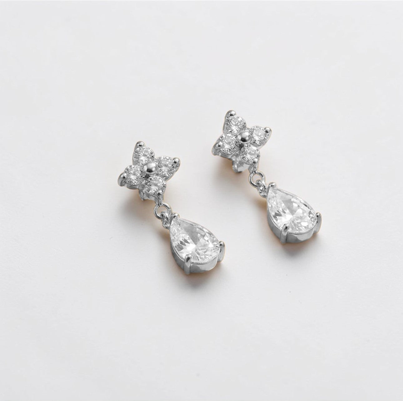 Pair of silver earrings with teardrop-shaped crystals on a white background