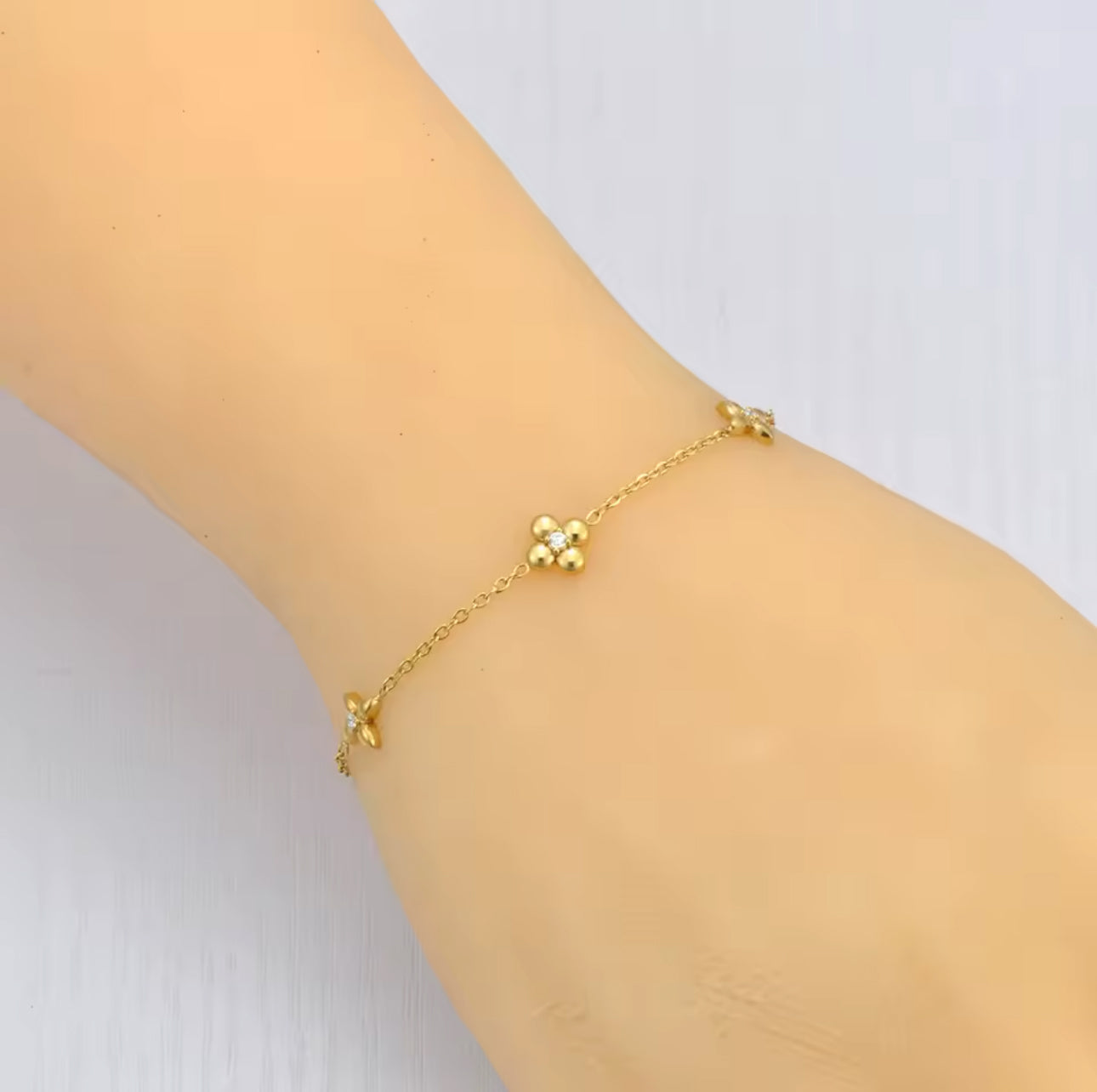 Gold bracelet with flower detail being worng on a wrist