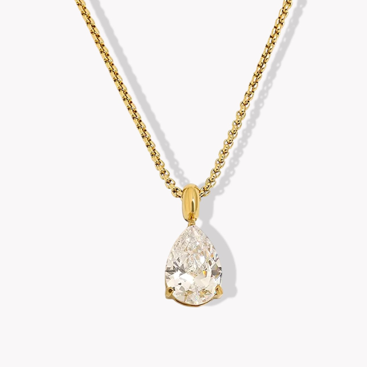 Gold necklace with a teardrop-shaped diamond pendant on a white background