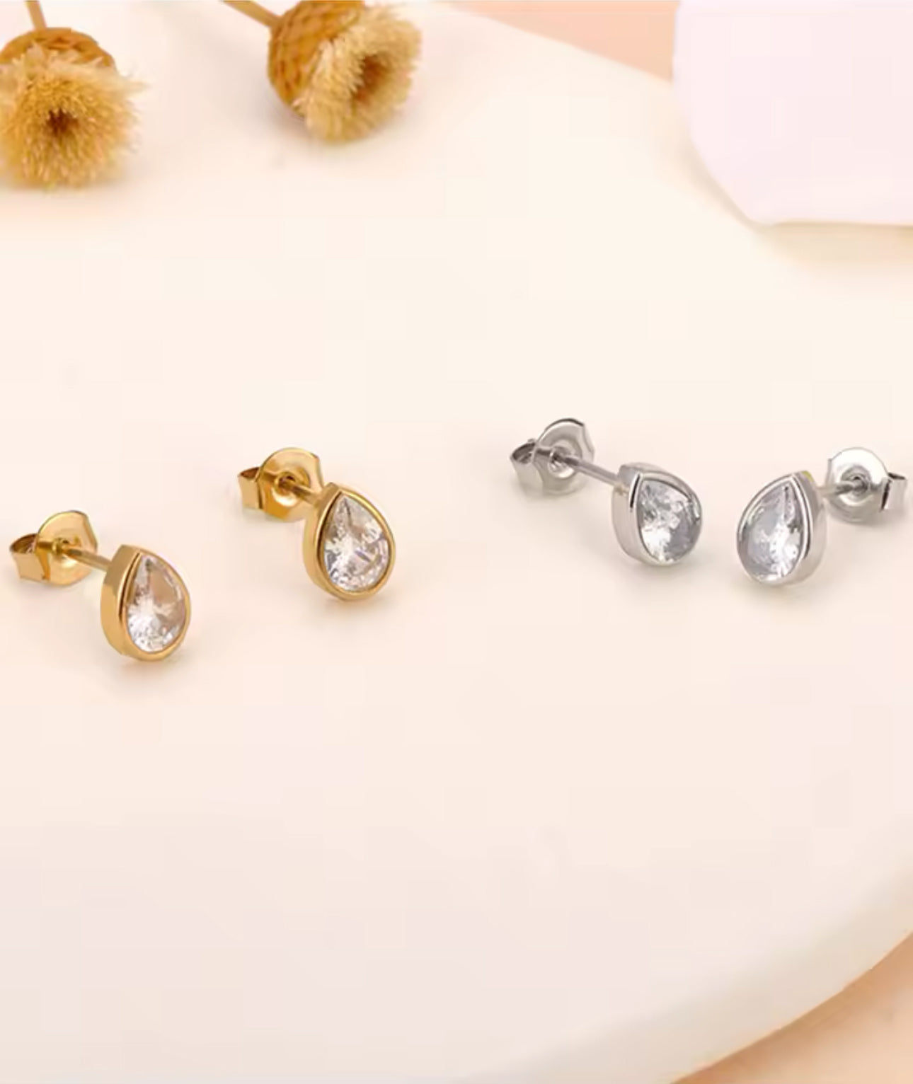 pair of gold and silver pear shaped stud earrings on a white background