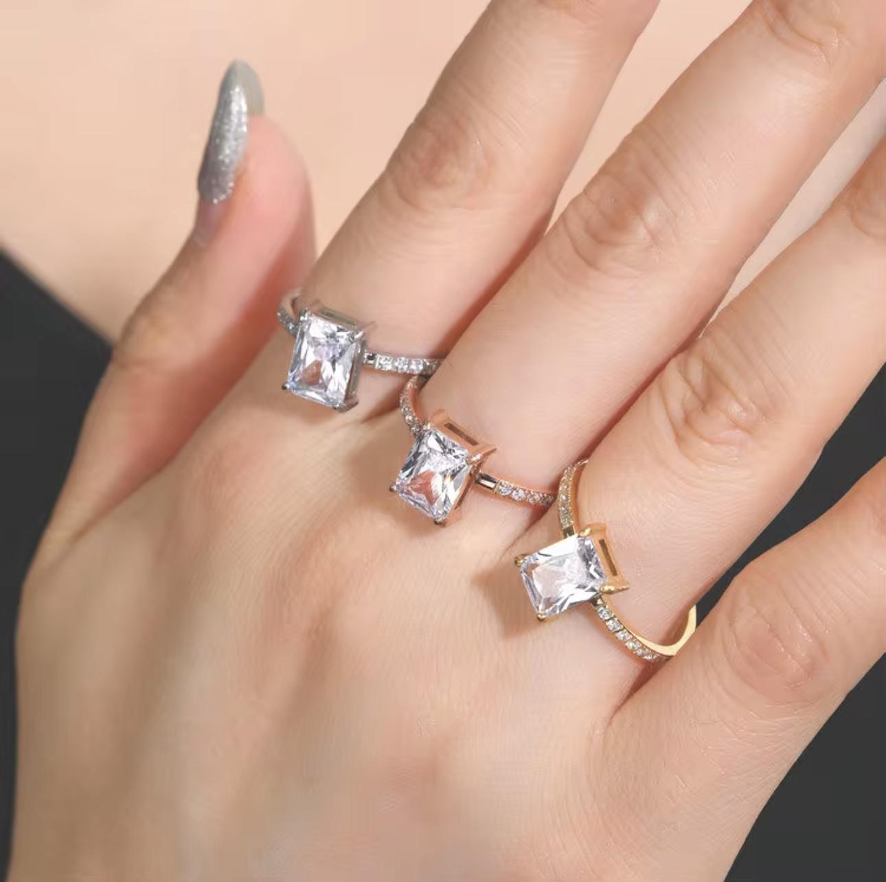 Three diamond rings on a hand against a neutral background