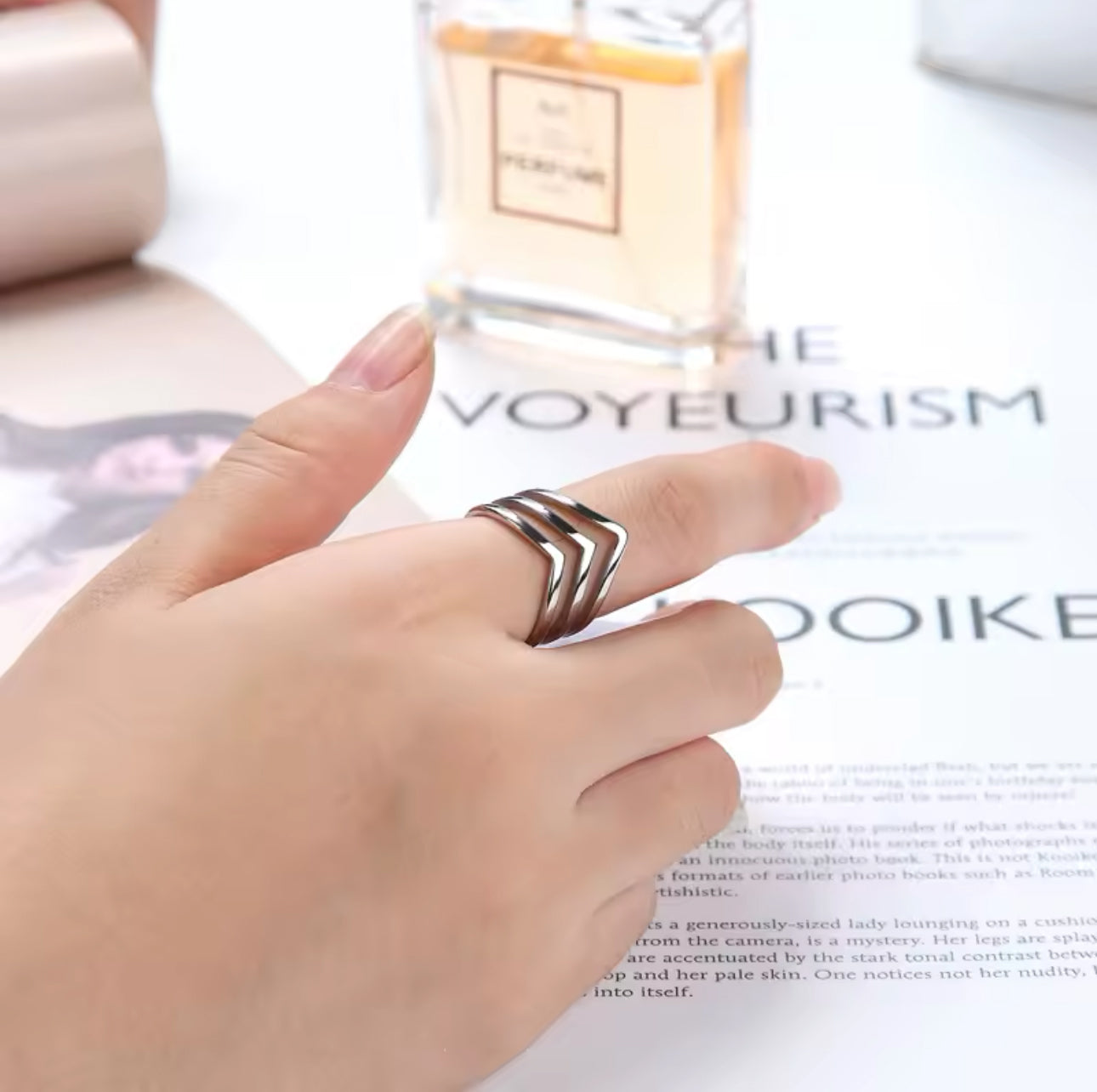 silver layered wishbone ring being worn on a finger with a magazine in the background