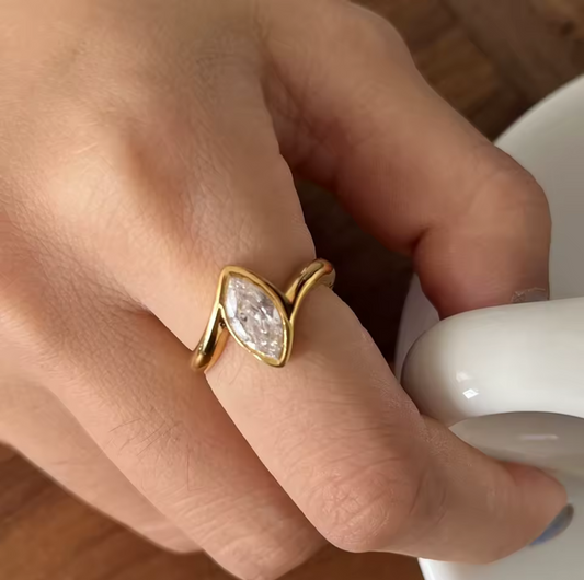 gold ring with a marquise shaped stone being worn on a finger