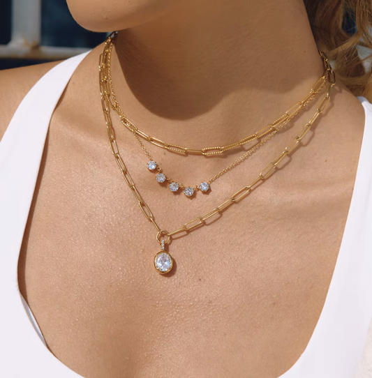 Close-up of a person wearing gold necklaces with diamond pendants.