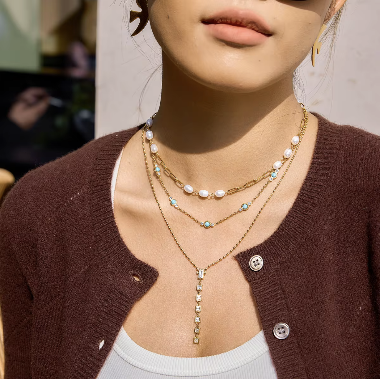 Close-up of a person wearing multiple necklaces with a blurred background