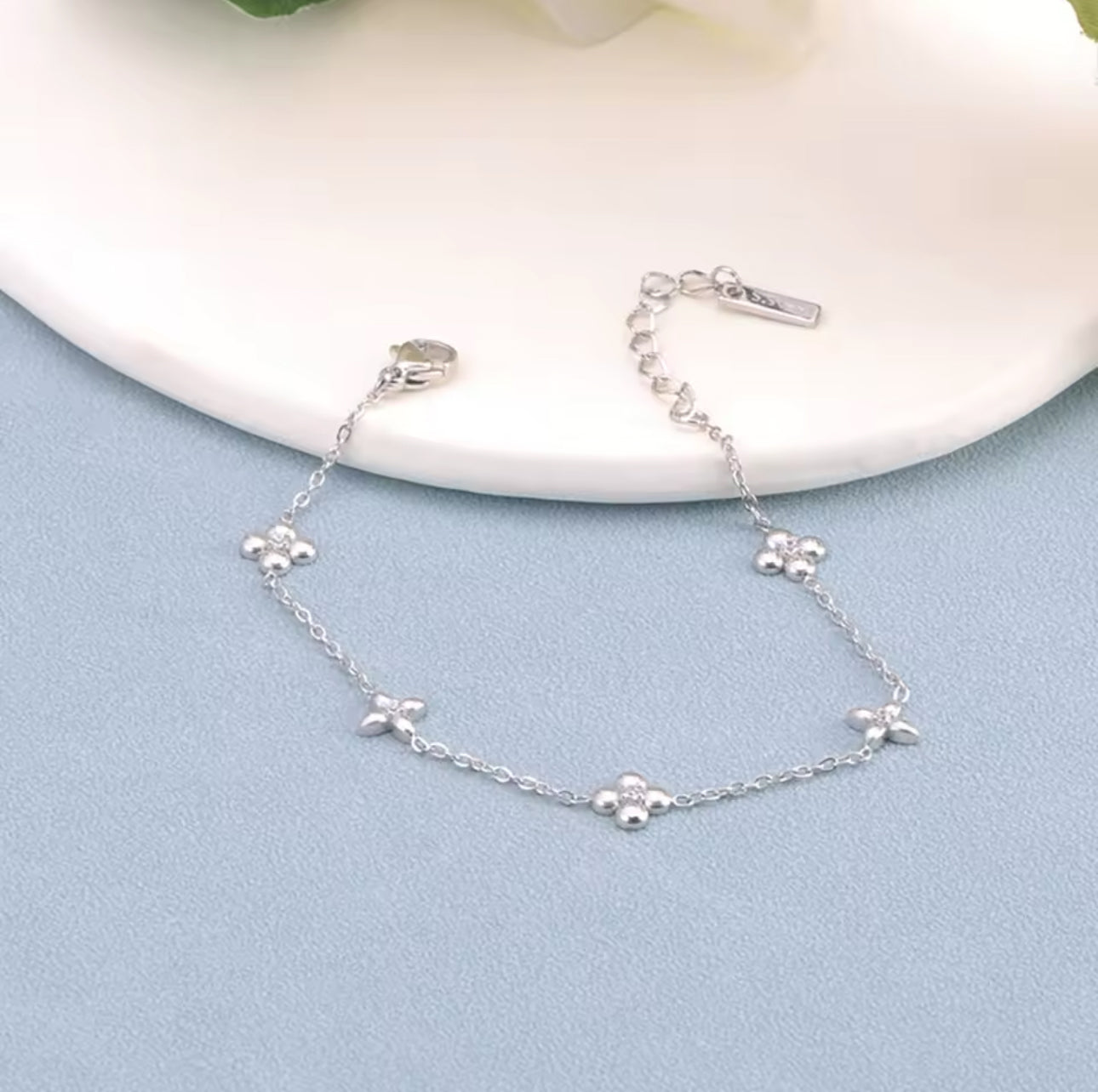 Silver bracelet with flower detail on a blue and white background