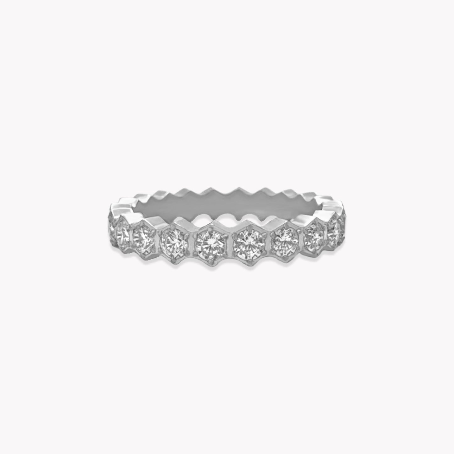 Silver ring with a full band of clear gemstones. The band has an hexagonal shape to it. Pictured on a white background