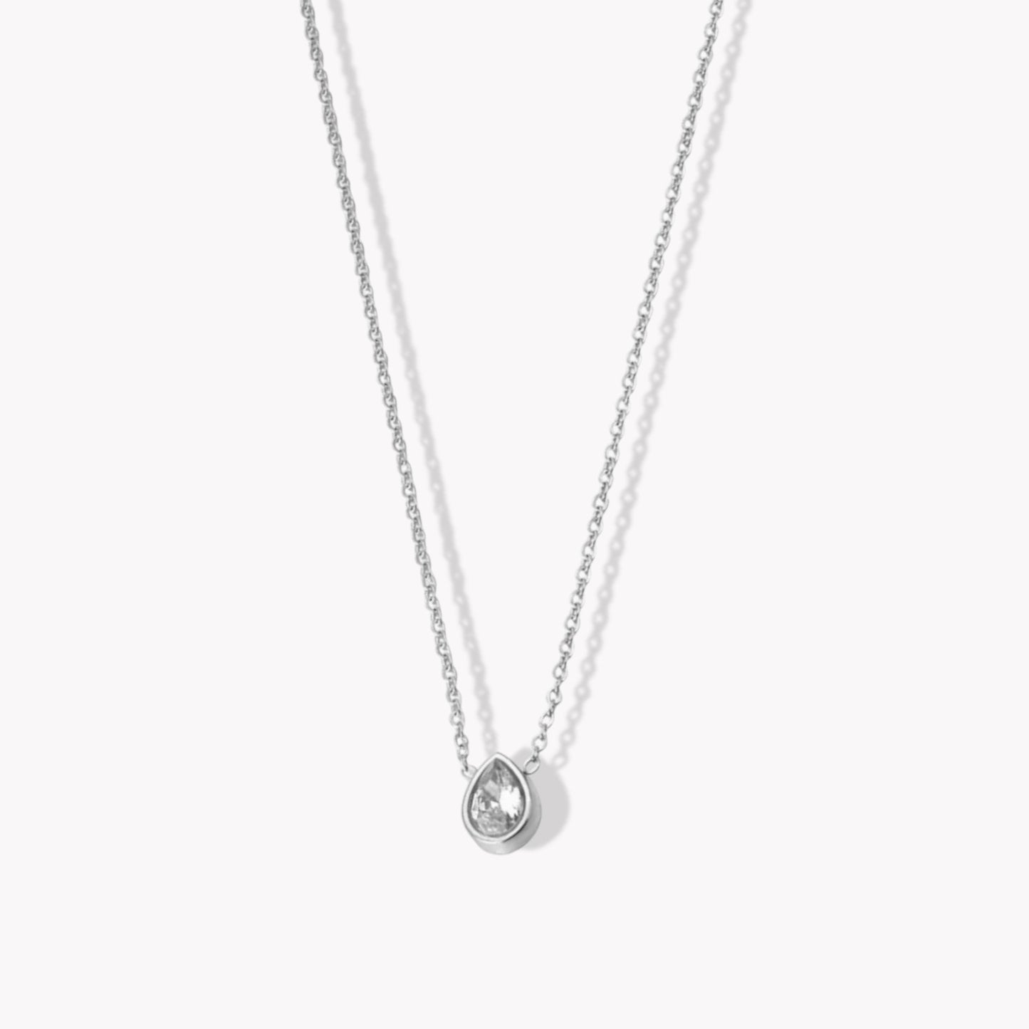 A silver necklace with a central pendant featuring a zircon pear shaped gemstone, attached to a fine chain.