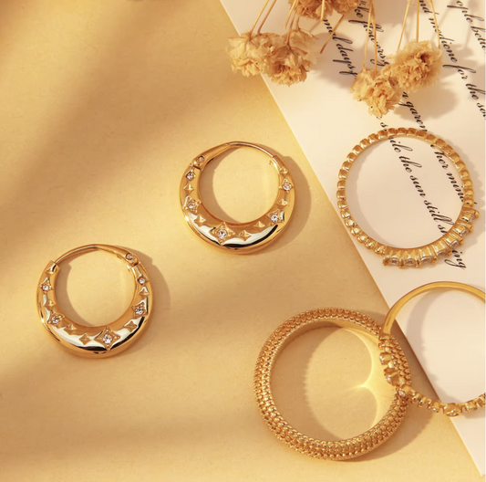 Gold hoop earrings on a yellow and white background with dried flowers.