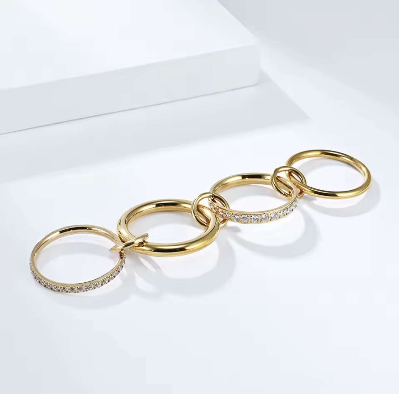 Gold layered link ring, featuring 4 bands - two plan silver and 2 with clear gemstones. Held together by three smaller links pictured on a white background