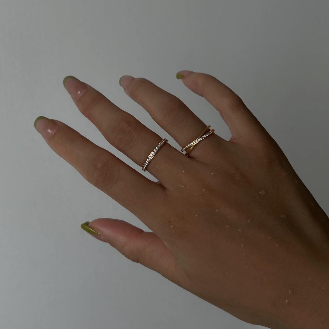 Hand with gold rings on a plain background