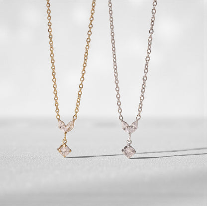Two necklaces, one gold and one silver. Both with a small marquise and round gemstone pendant on a light grey background