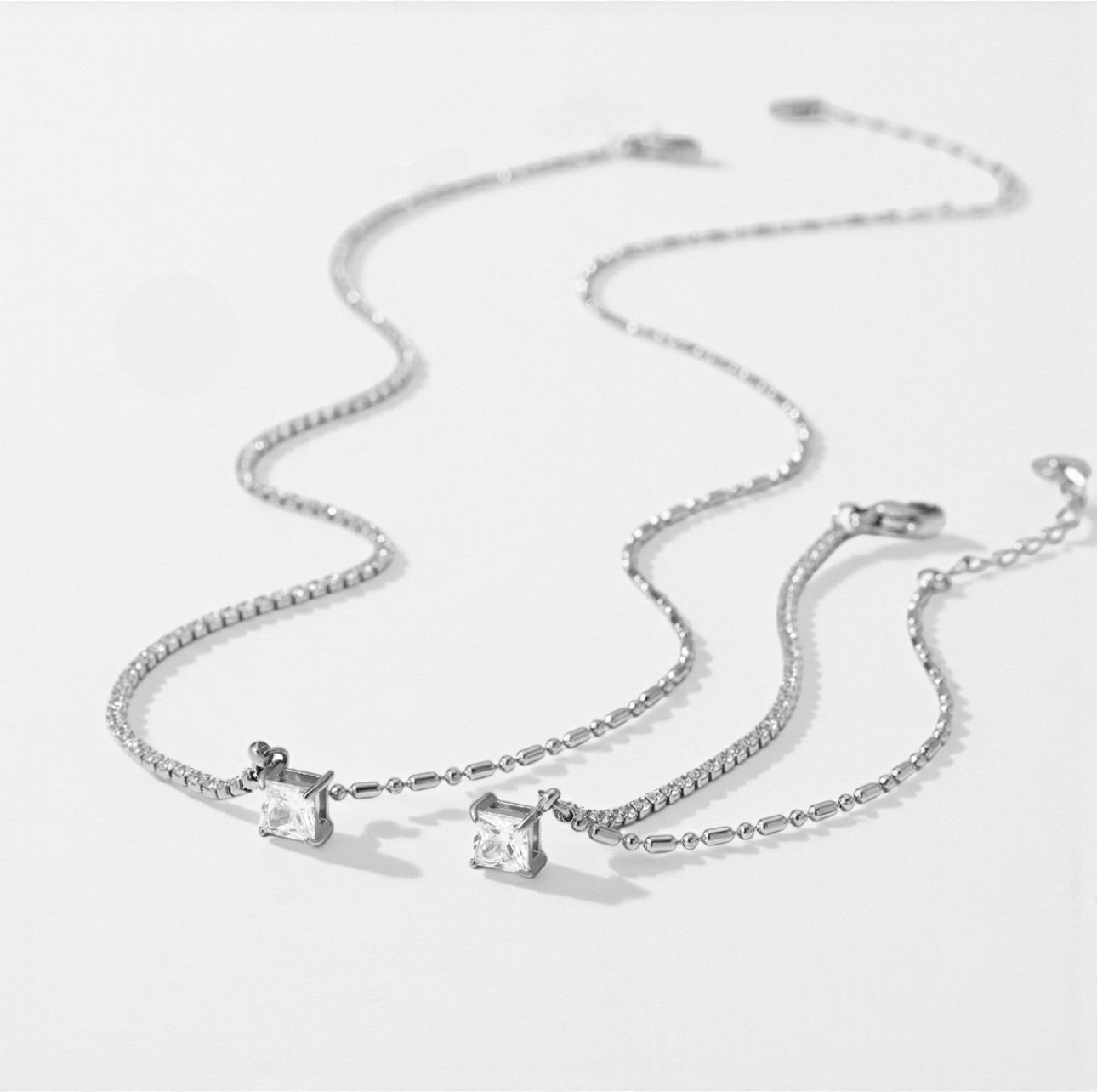 Silver necklace with two pendant stones on a light gray background