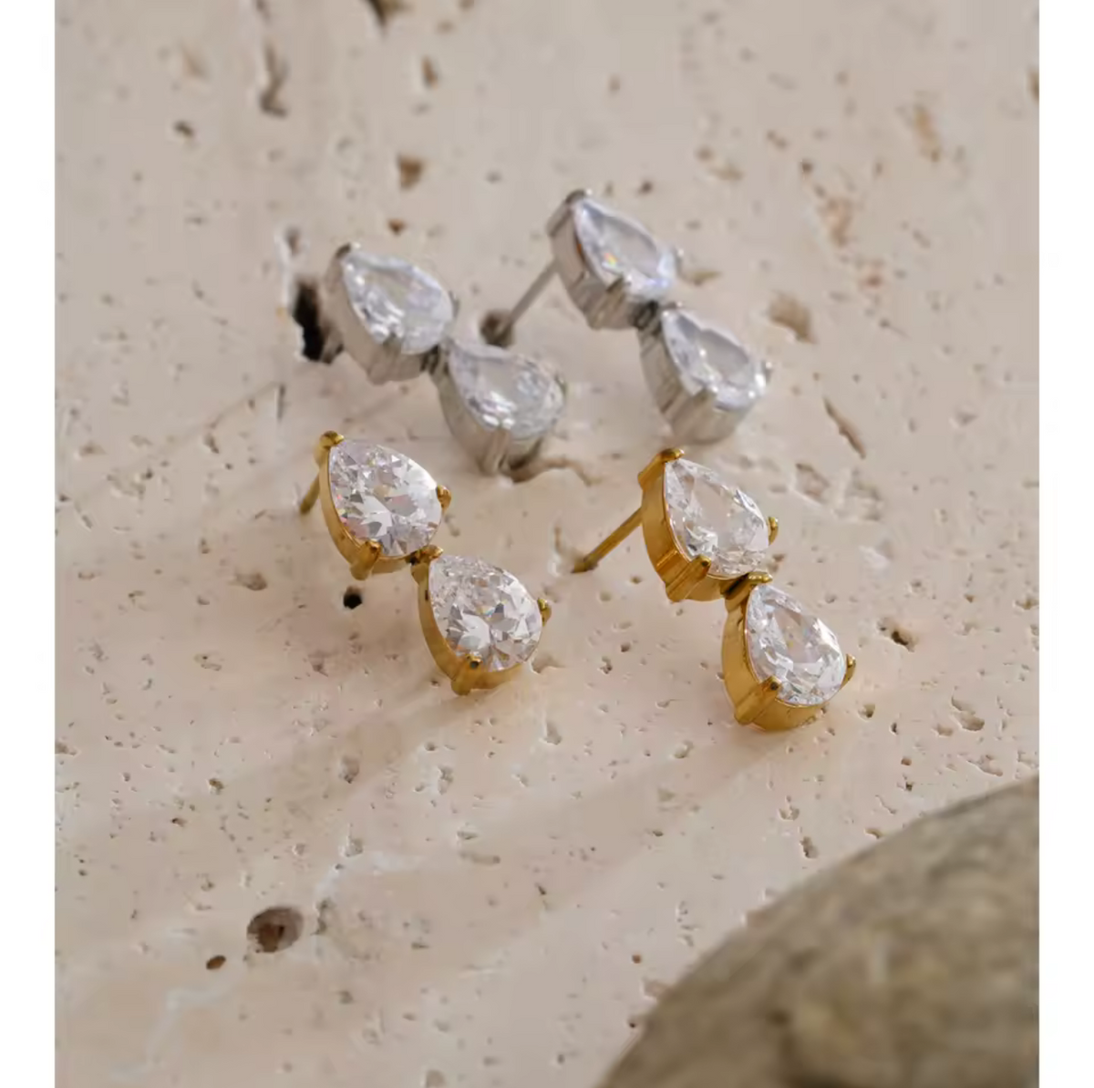Pair of diamond stud earrings on a textured beige surface