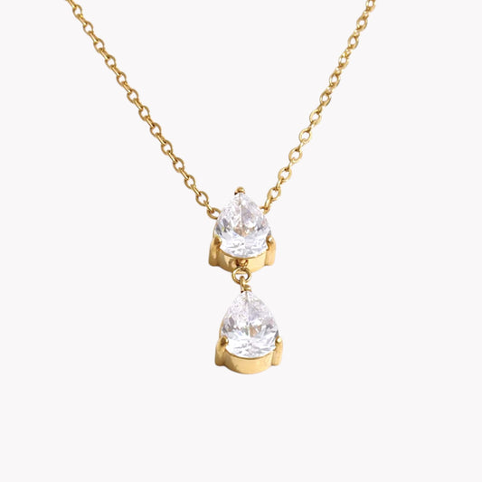 Close up of a necklace with 2 pear shaped gemstones on a light grey background