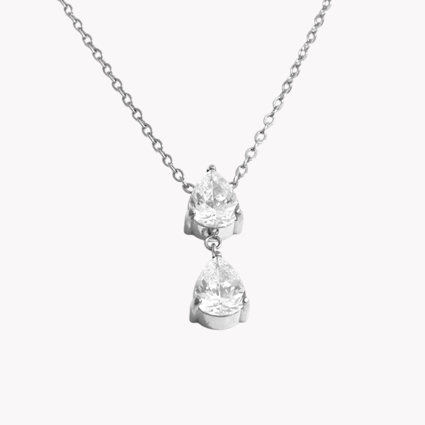 Close up of a necklace with 2 pear shaped gemstones on a light grey background