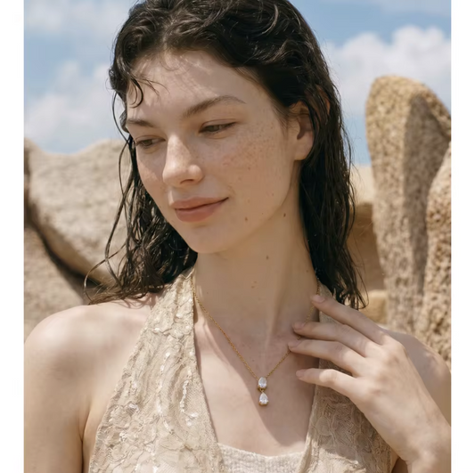Close up of a necklace with 2 pear shaped gemstones being worn