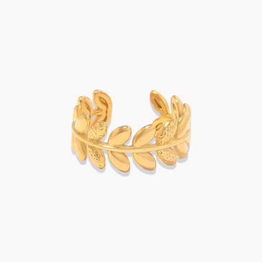 An 18k gold ring with leaf sculpted details around the band, displayed on a white background.