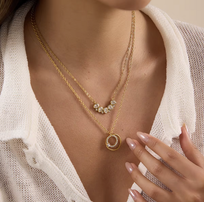 Close up of a gold necklace with circular pendant being worn