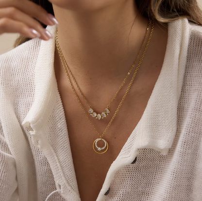Close up of a gold necklace with circular pendant being worn