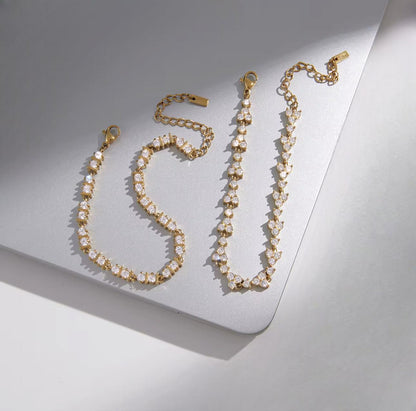 two gold bracelets with clear gemstones pictured together on a grey background