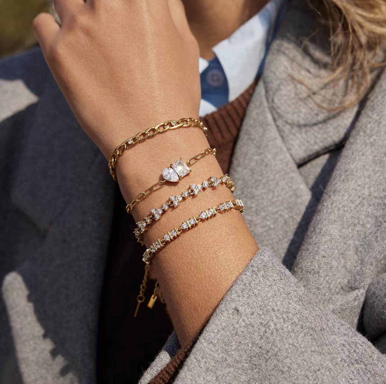 Close-up of a person's wrist wearing multiple gold and diamond bracelets.