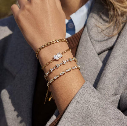Close-up of a person's wrist wearing multiple gold and diamond bracelets.