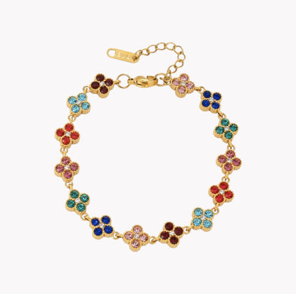 A gold-plated bracelet featuring a series of small, colorful flower-shaped links, each set with multiple round rhinestones in shades of blue, pink, red, green, and brown, displayed on a clean white background.