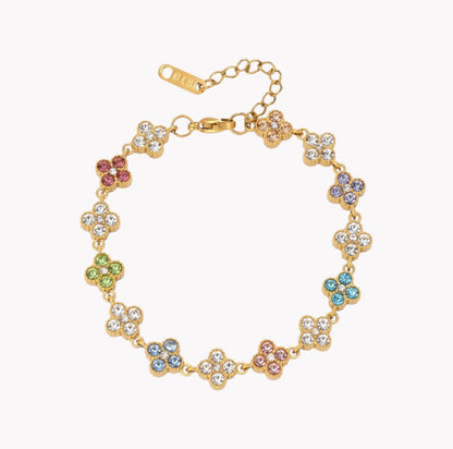 A gold-plated flower bracelet with clear rhinestones and small multicolor accent stones, shown on a light gray background.