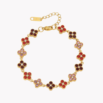 A gold-tone floral bracelet with alternating red, dark brown, and light pink rhinestone clover motifs, shown on a plain white background.