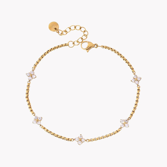 Gold bracelet with small floral charms on a white background