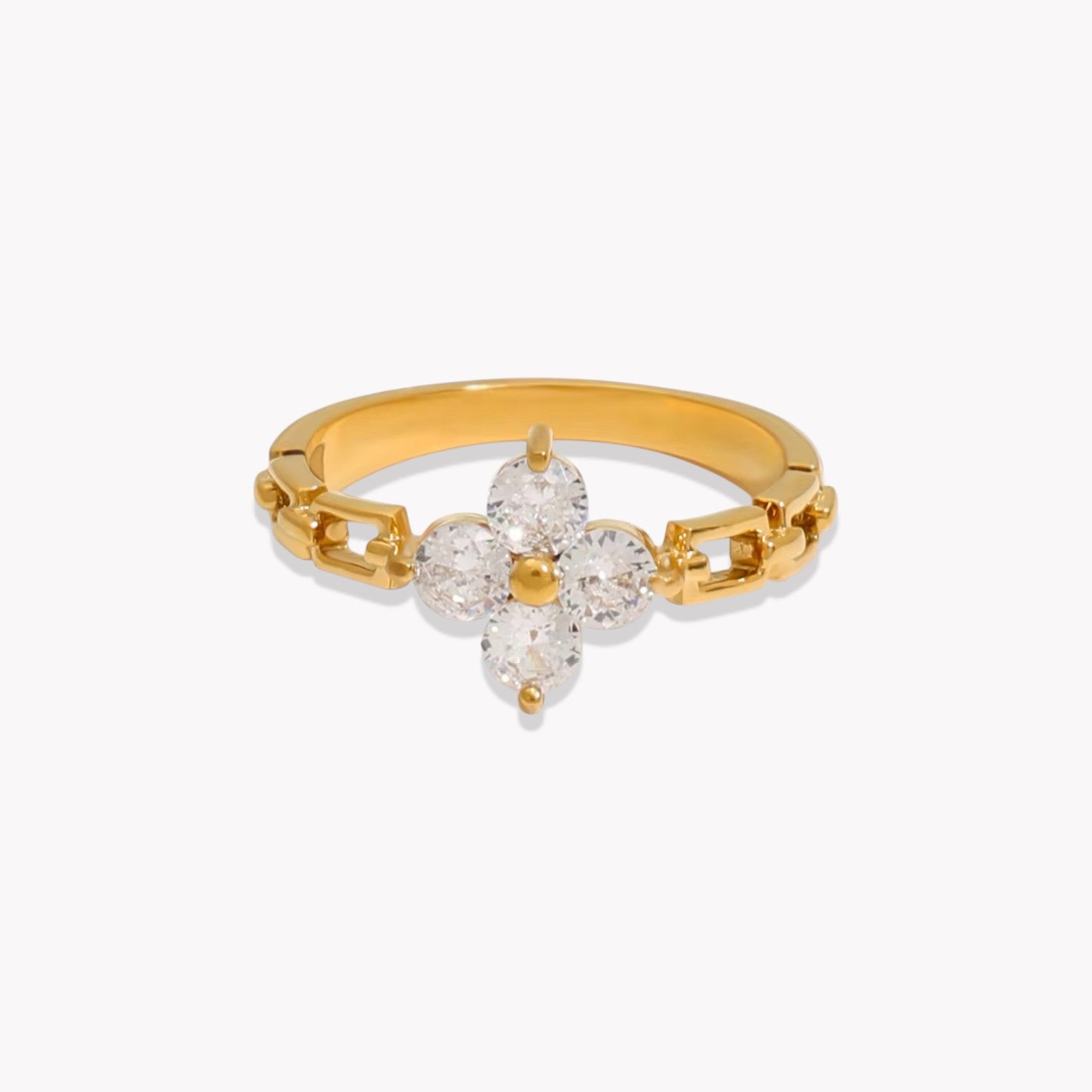A gold-colored ring with a white gemstone floral design in the center, featuring a gold band with small embellishments.