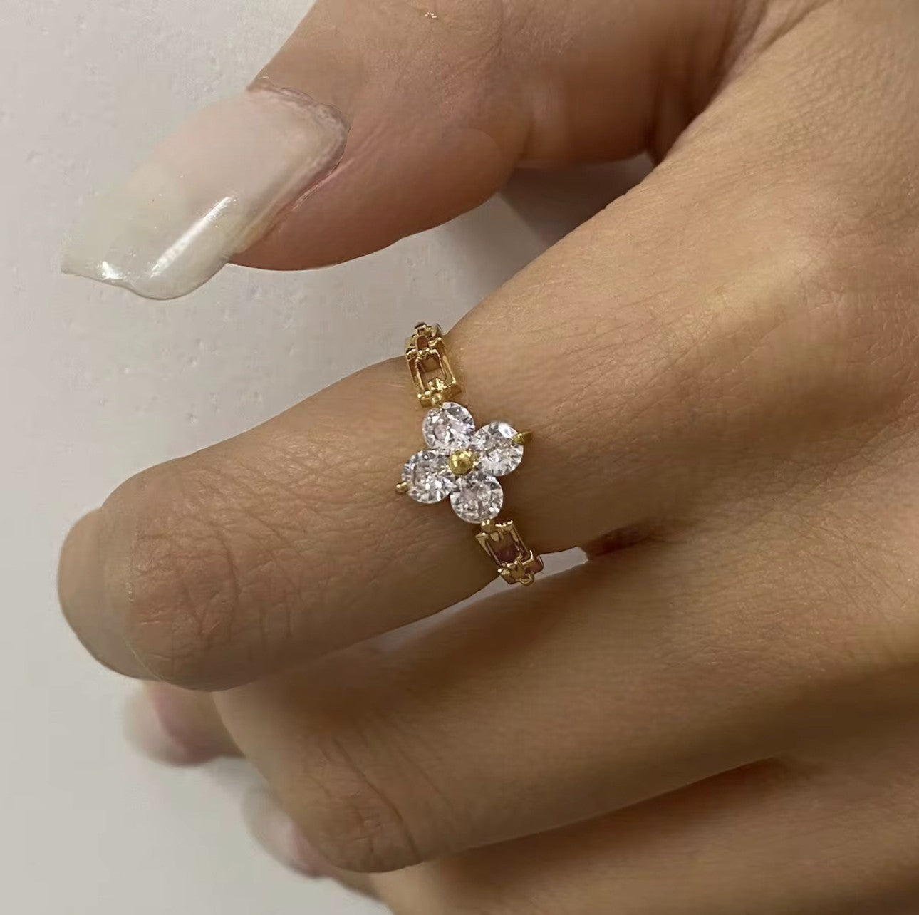 Ring featuring floral gemstone detail being worn on a finger