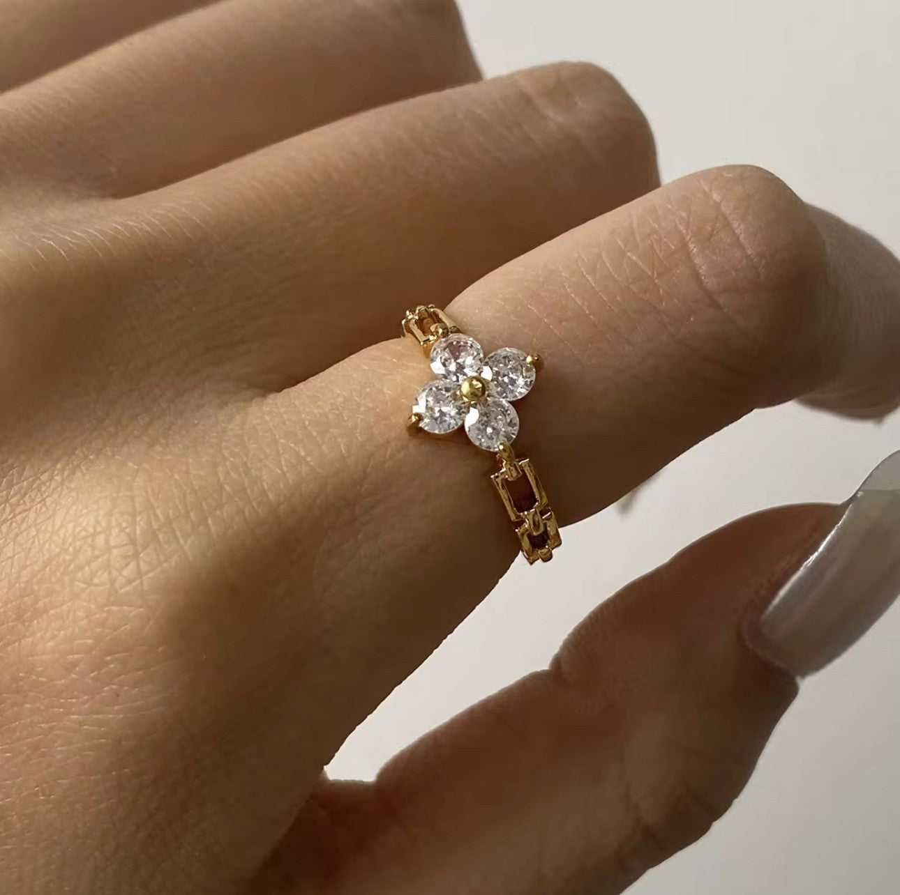 Ring featuring floral gemstone detail being worn on a finger