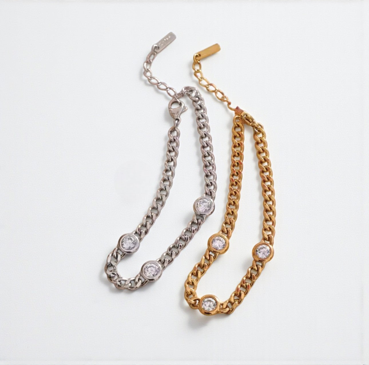 Two chain necklaces, one gold and one silver, on a white background