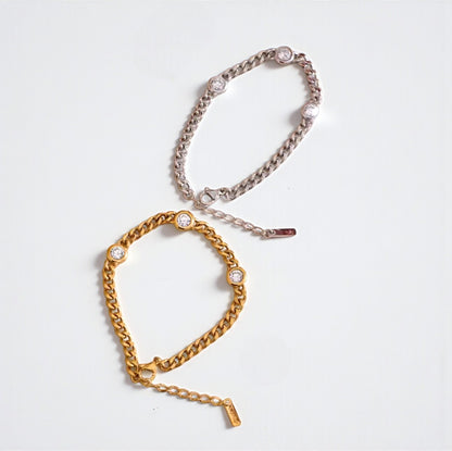 Gold and silver chain bracelets on a light grey background