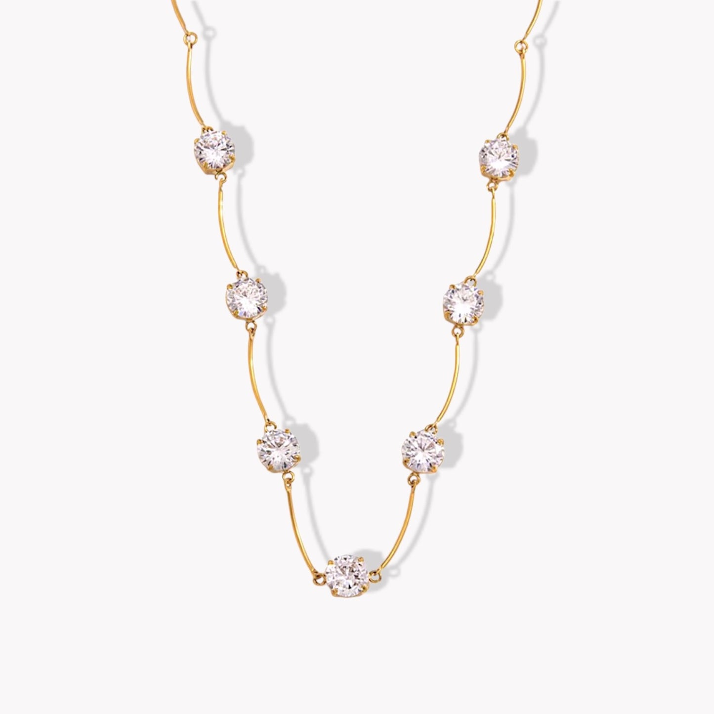 Gold necklace with clear gemstones on a white background