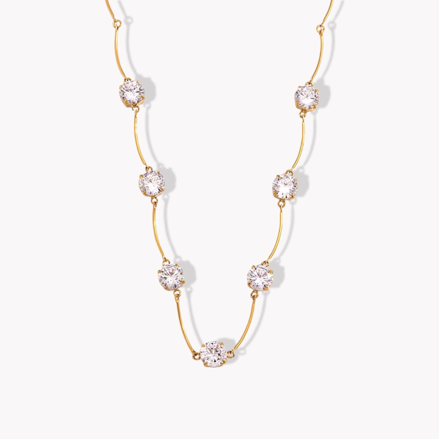 Gold necklace with clear gemstones on a white background