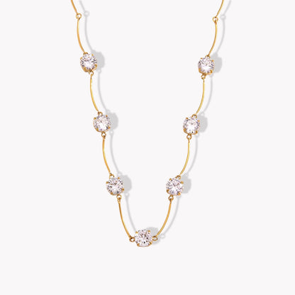 Gold necklace with clear gemstones on a white background