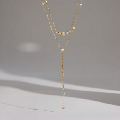 gold double layered necklace with clear gemstones pictured on a grey background