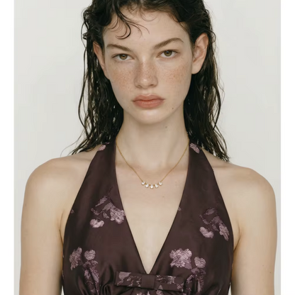 gold necklace featuring a row of 5 small pear shaped gemstones pictured being worn around the neck