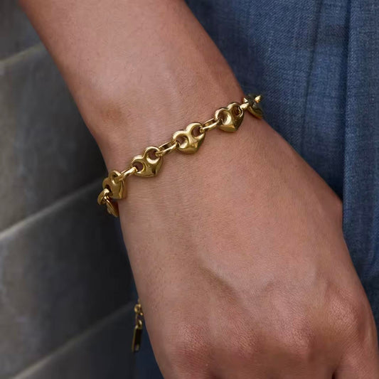 Gold chunky chain bracelet with heart chaped links being worn on a wrist