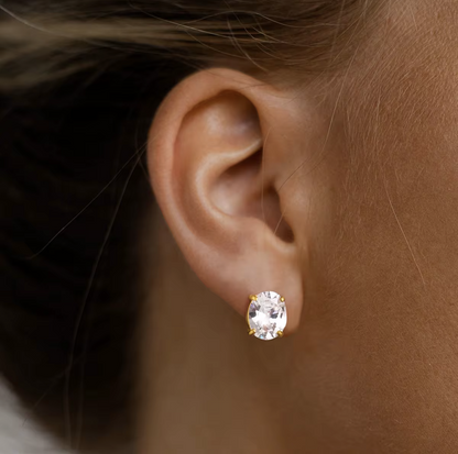 Close-up of an ear wearing a diamond stud earring with a blurred background