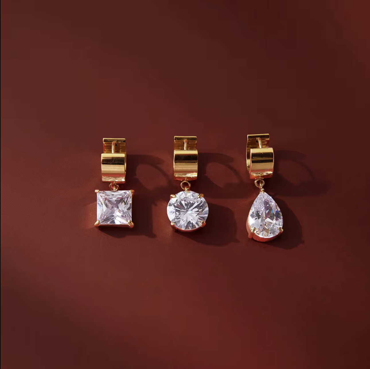 numerous gold earrings with gemstones on a red background