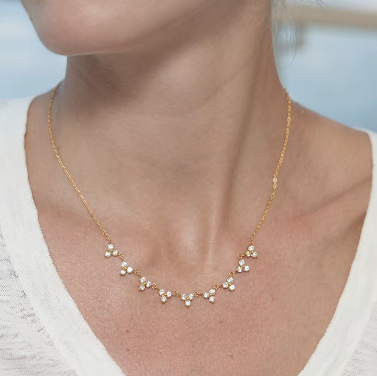 Gold necklace with small pearls worn by a person against a blurred background