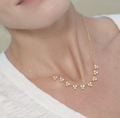 Gold necklace with small pearls worn by a person against a neutral background